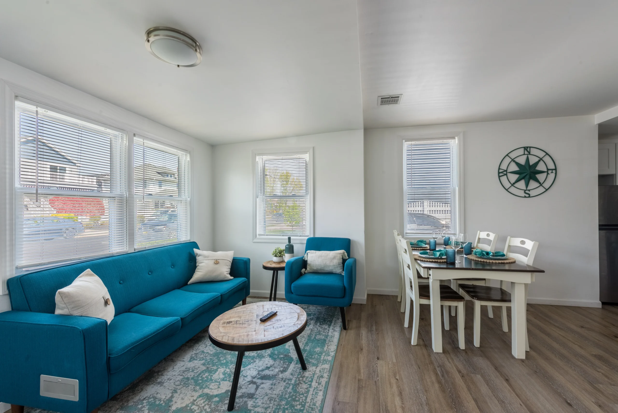 Coastal living room with teal sectional sofa, nautical decor, and bright windows in Belmar beach house