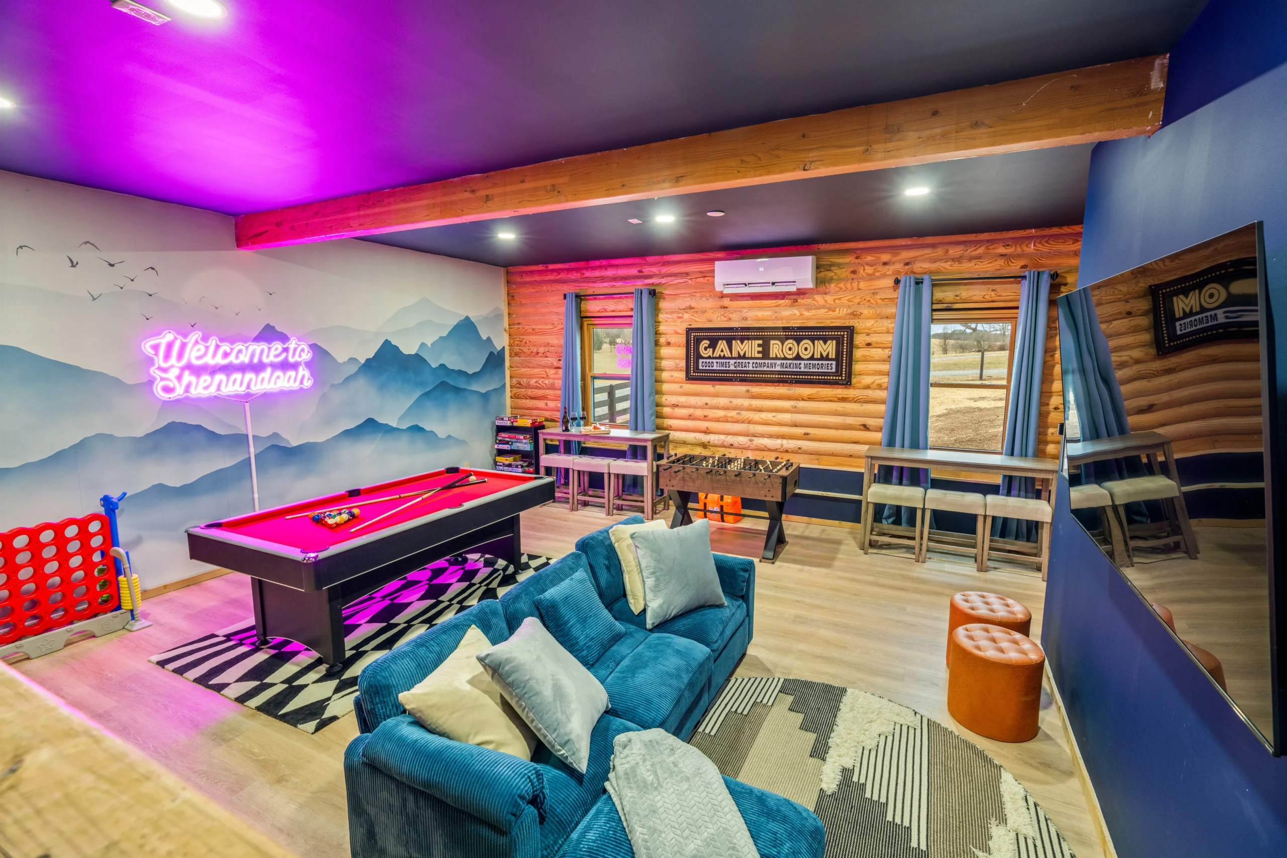 Game room with neon pink lighting, pool table, foosball table, and blue seating at Skyline Vista Retreat, a Luray, VA rental