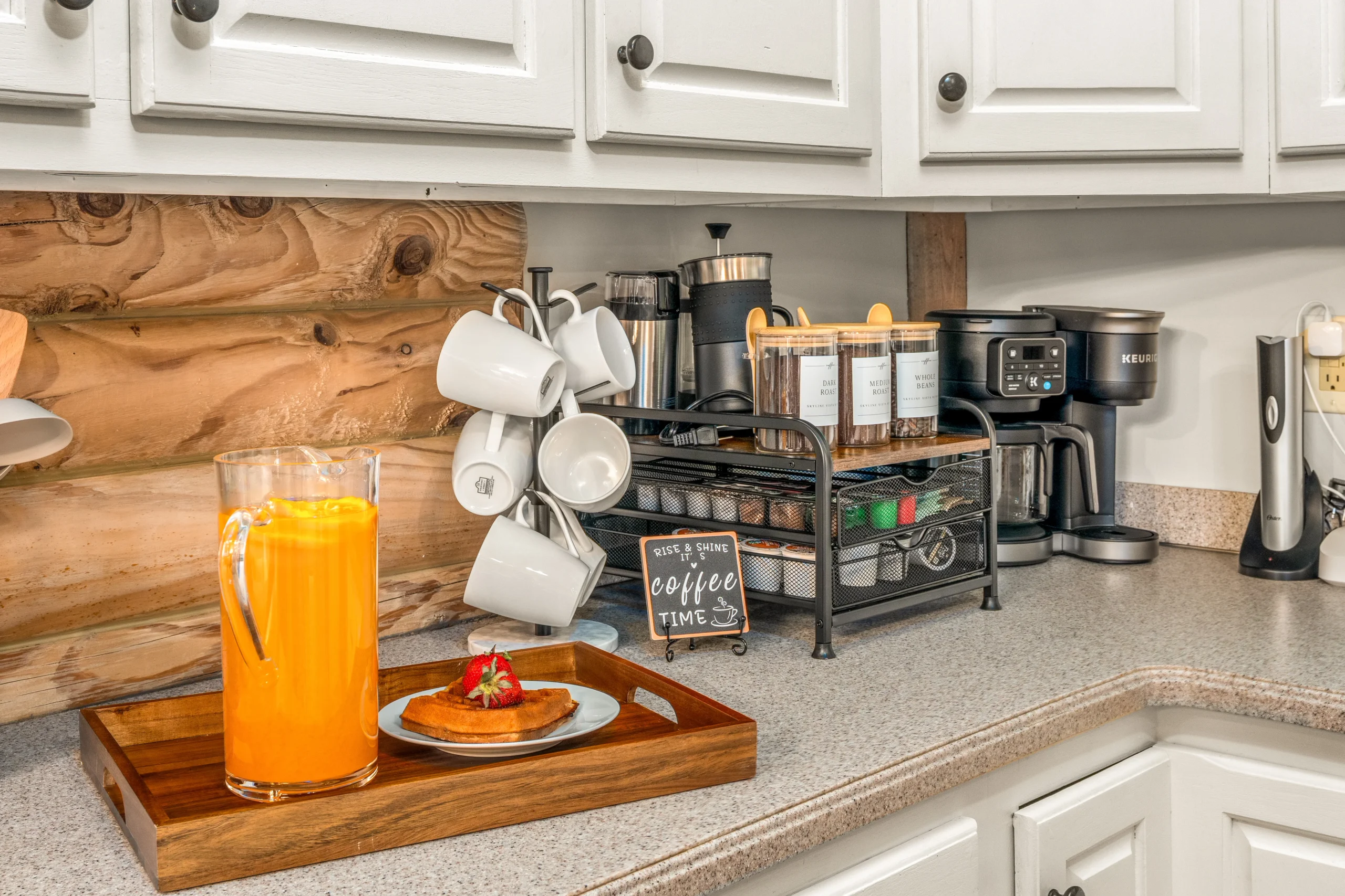 Modern kitchen coffee station with Keurig, mugs, and orange juice on a wood tray in a Luray, VA rental by Endless Stays