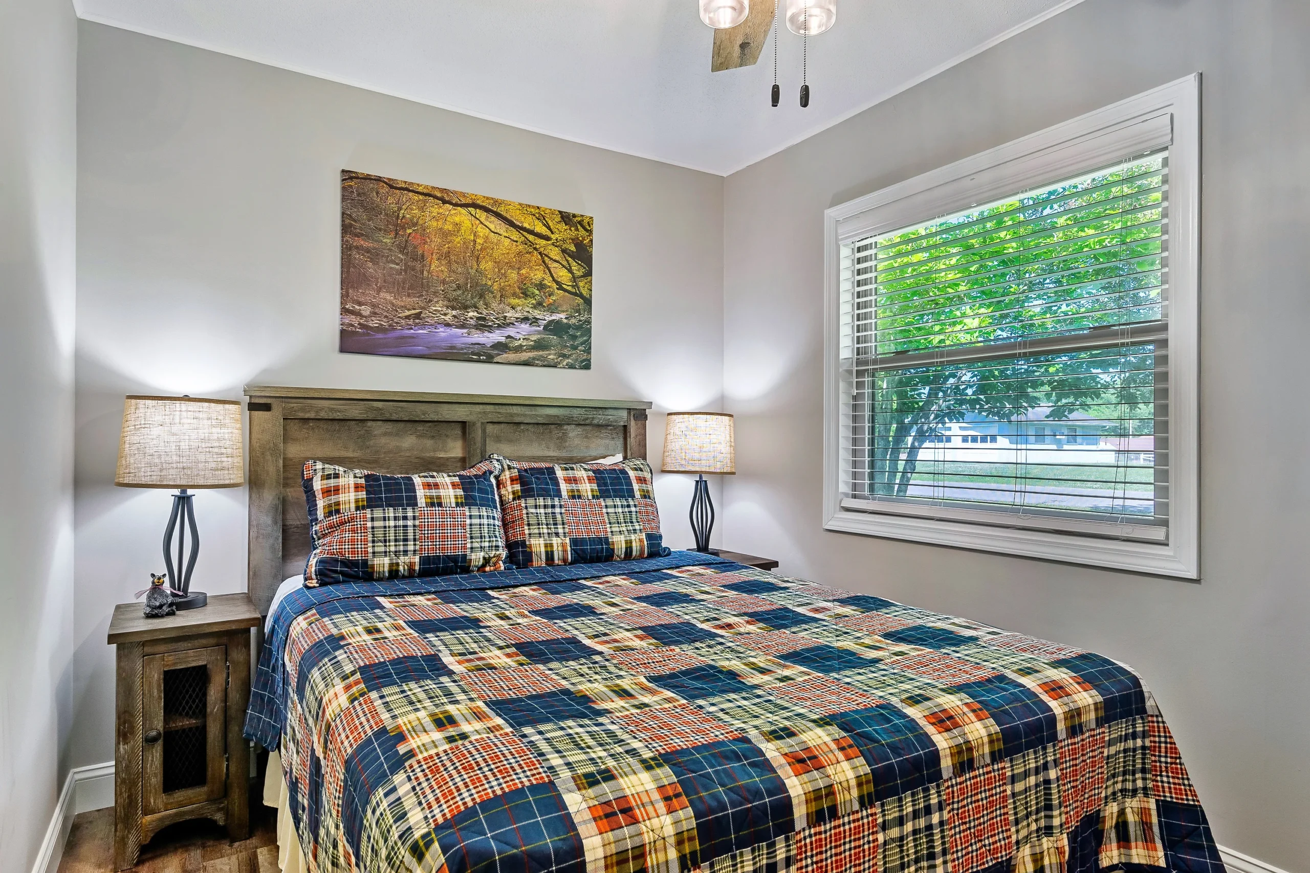 Bedroom with rustic wooden bed and navy, orange, and cream plaid bedding in a Pigeon Forge cabin with hot tub access,