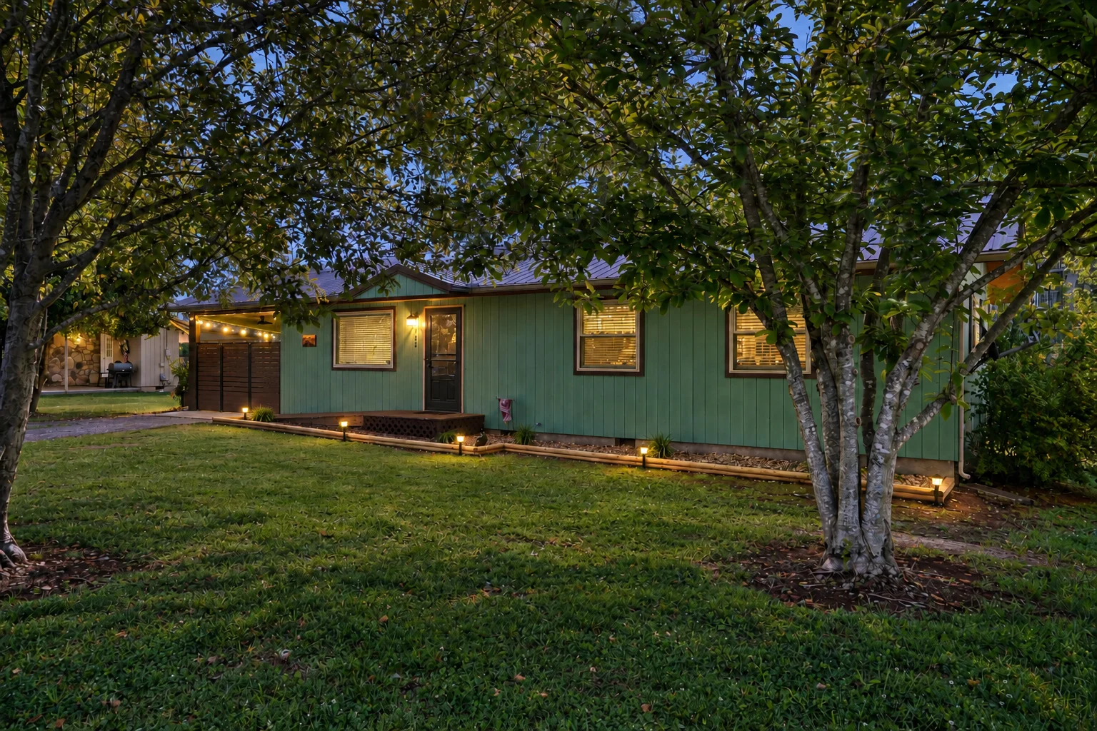 Green cottage exterior at dusk with warm lighting and shade trees, a shenandoah national park cabins stay from Endless Stays