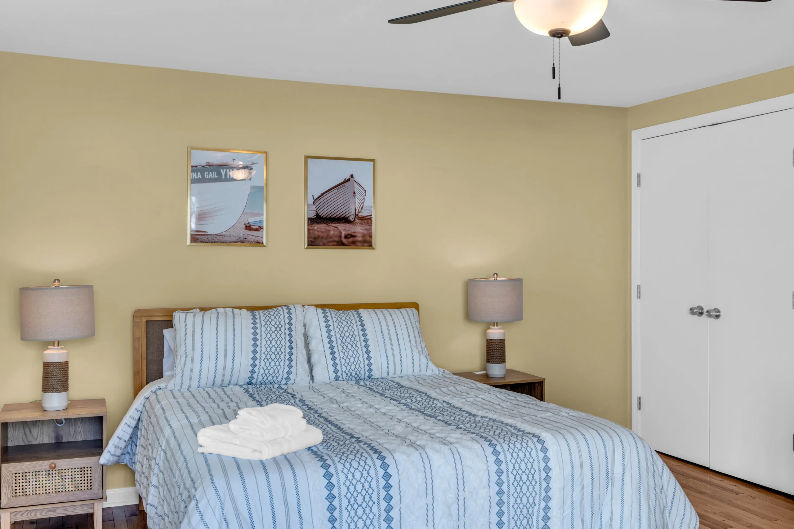 Coastal bedroom with queen bed, striped bedding, and nautical artwork at The Bradley Breeze