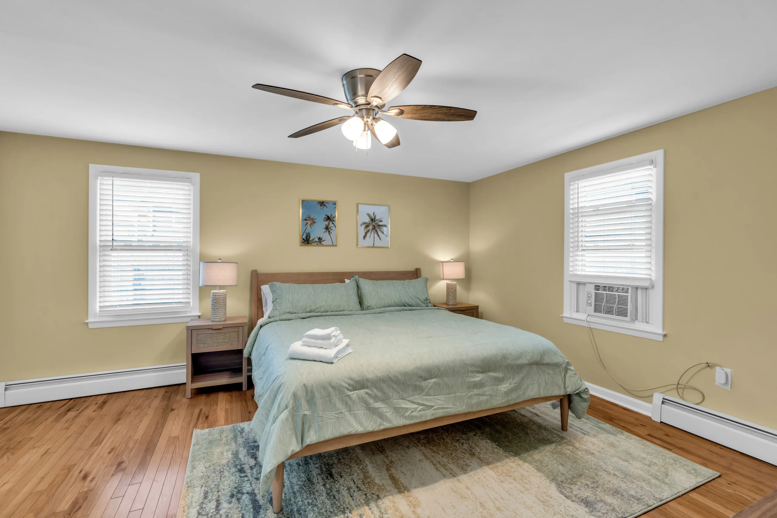 Bright coastal bedroom with yellow walls and hardwood floors at The Bradley Breeze in Bradley Beach