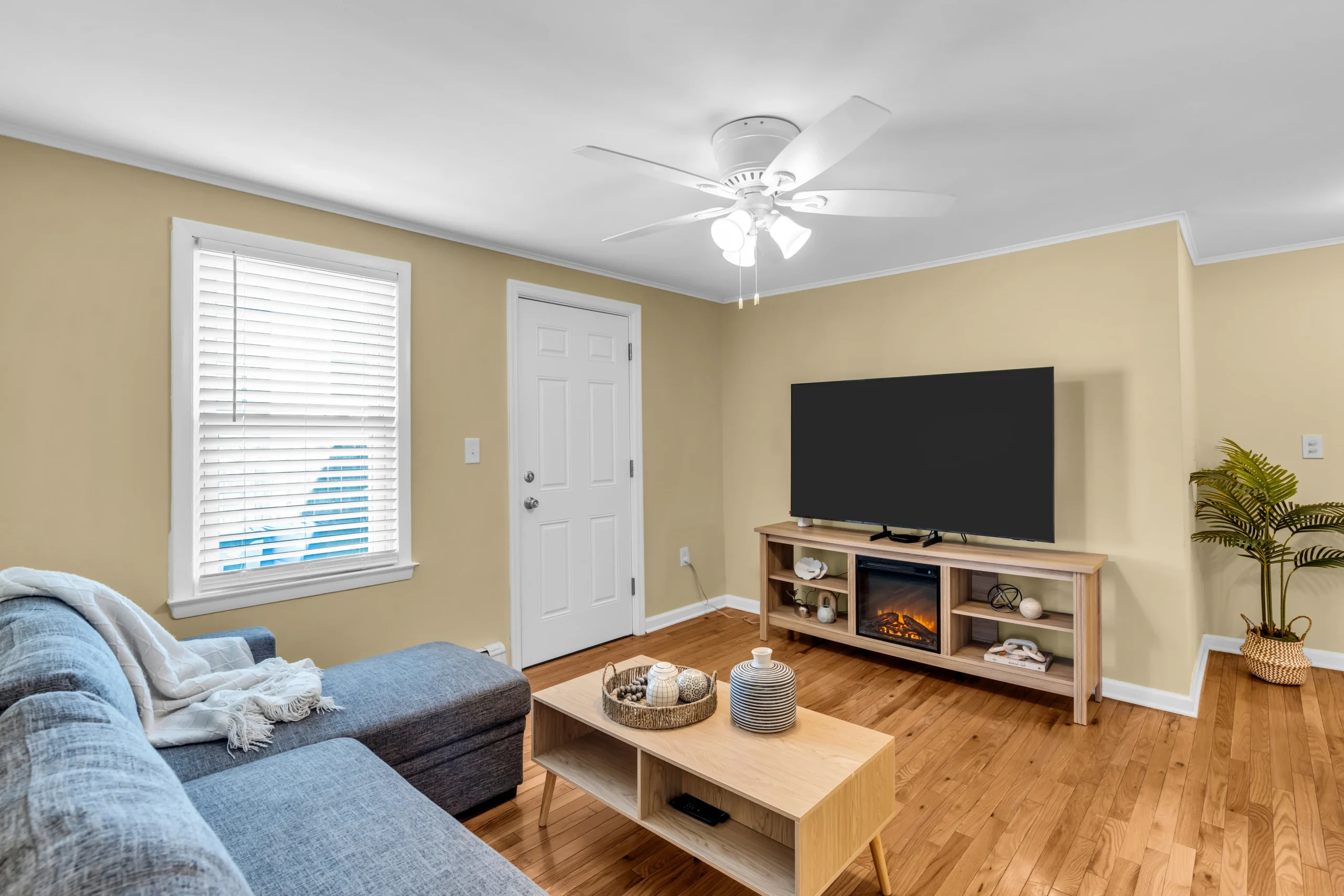 Bright modern living room with gray sectional, hardwood floors, and fireplace at Bradley Beach vacation rental