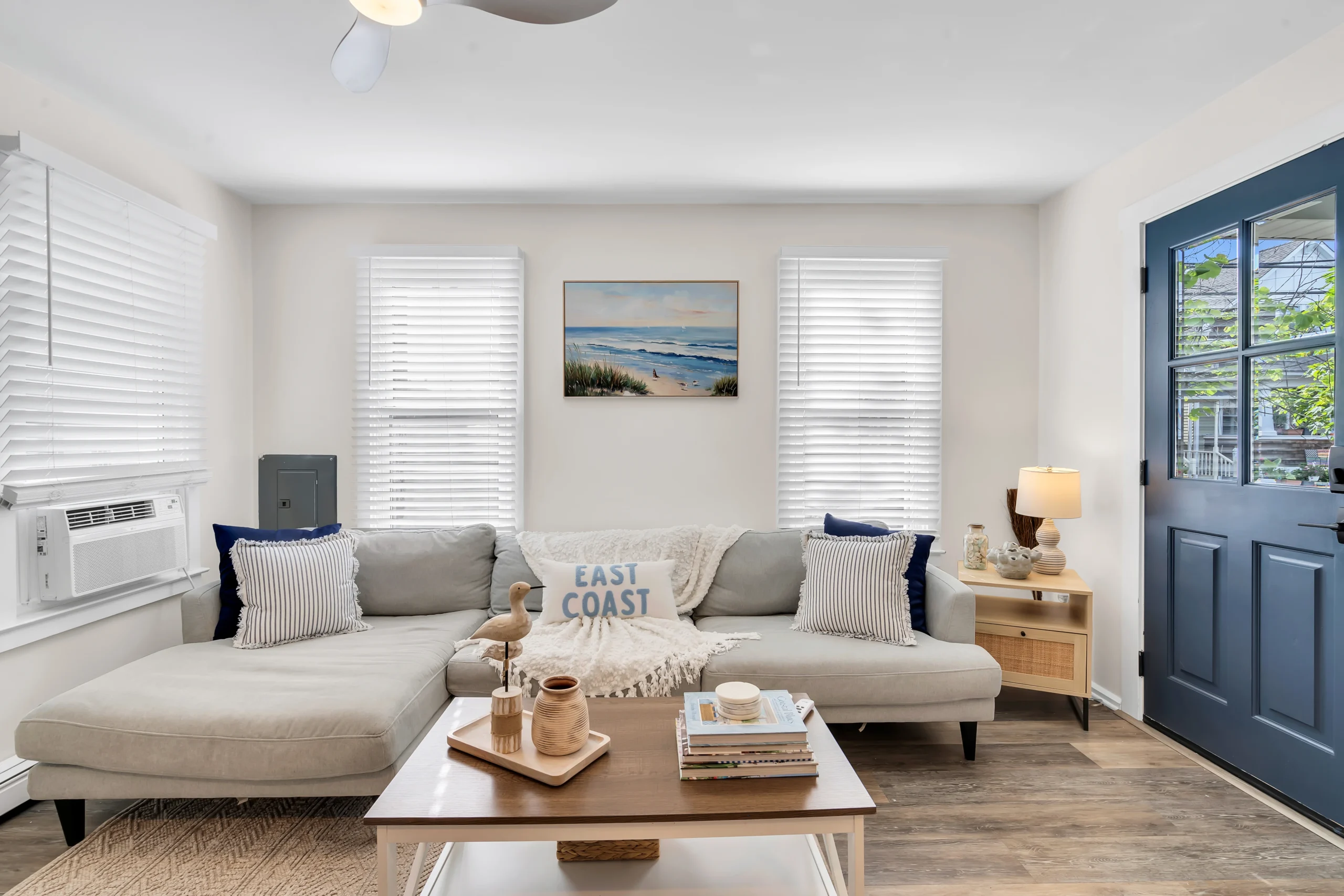 Coastal living room with light gray sectional, blue French doors in Ocean Grove Victorian rental