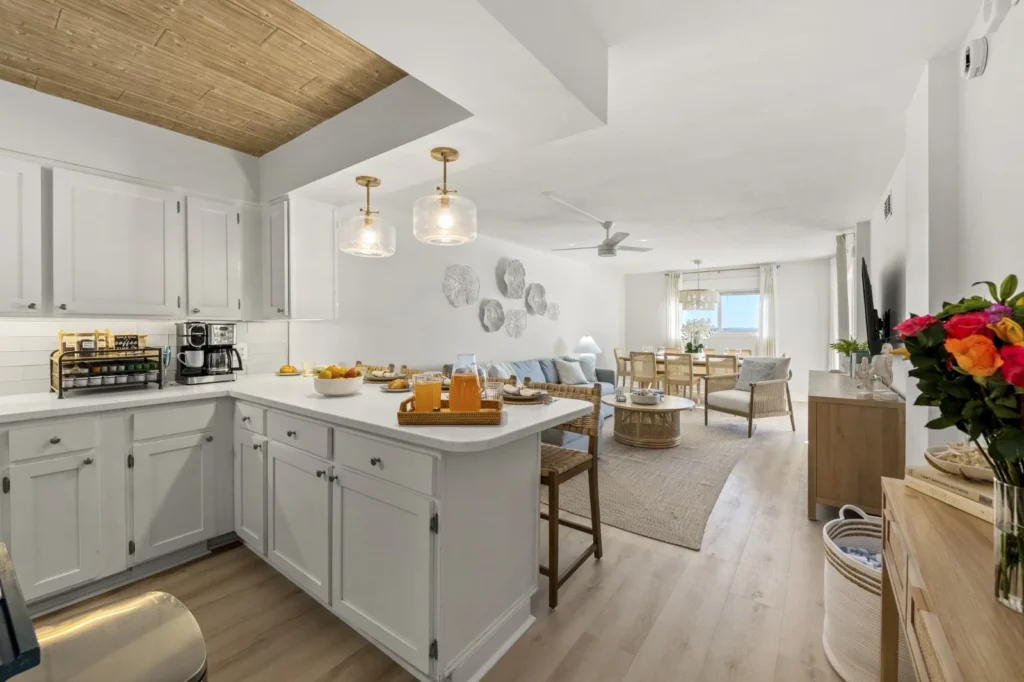 Open-concept coastal kitchen with white cabinets, island seating, and ocean views in The Regency Breeze, a Panama City Beach
