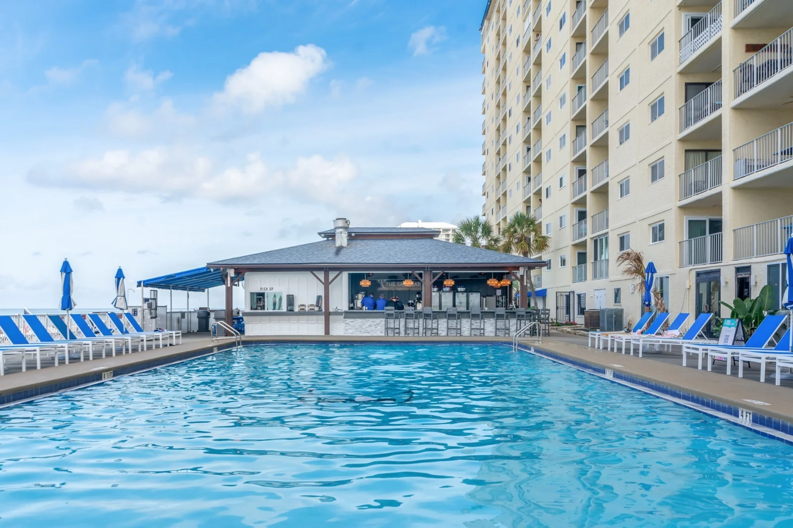 Resort pool with lounge chairs and tiki bar at family-friendly condo in Panama City Beach FL