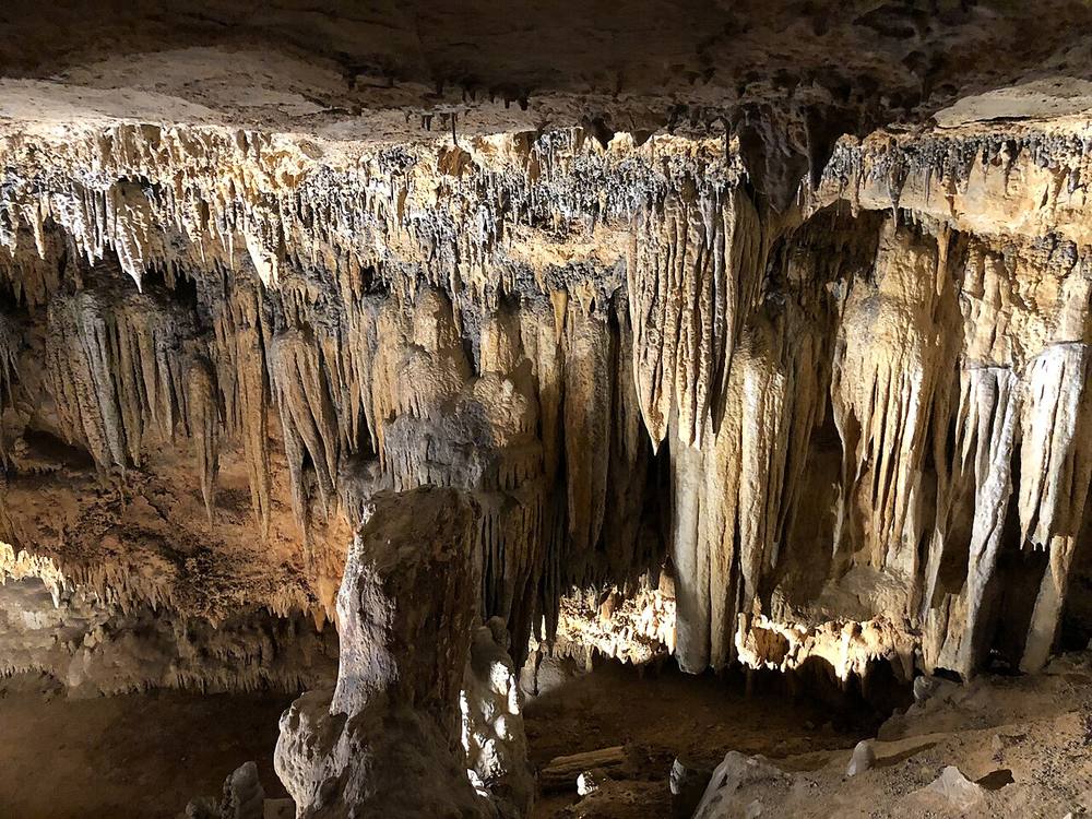 Illuminated stalactite and stalagmite rock formations reflected in a still pool inside Luray Caverns