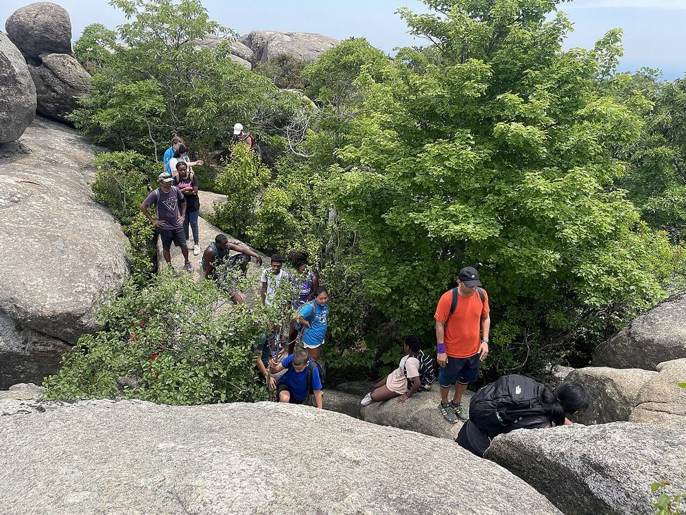 Hikers scrambling over large granite boulders near the summit of Old Rag Mountain