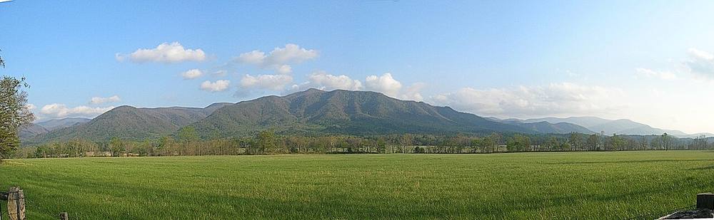The Cades Cove valley floor ringed by mountains, at the far end of Wears Valley Road