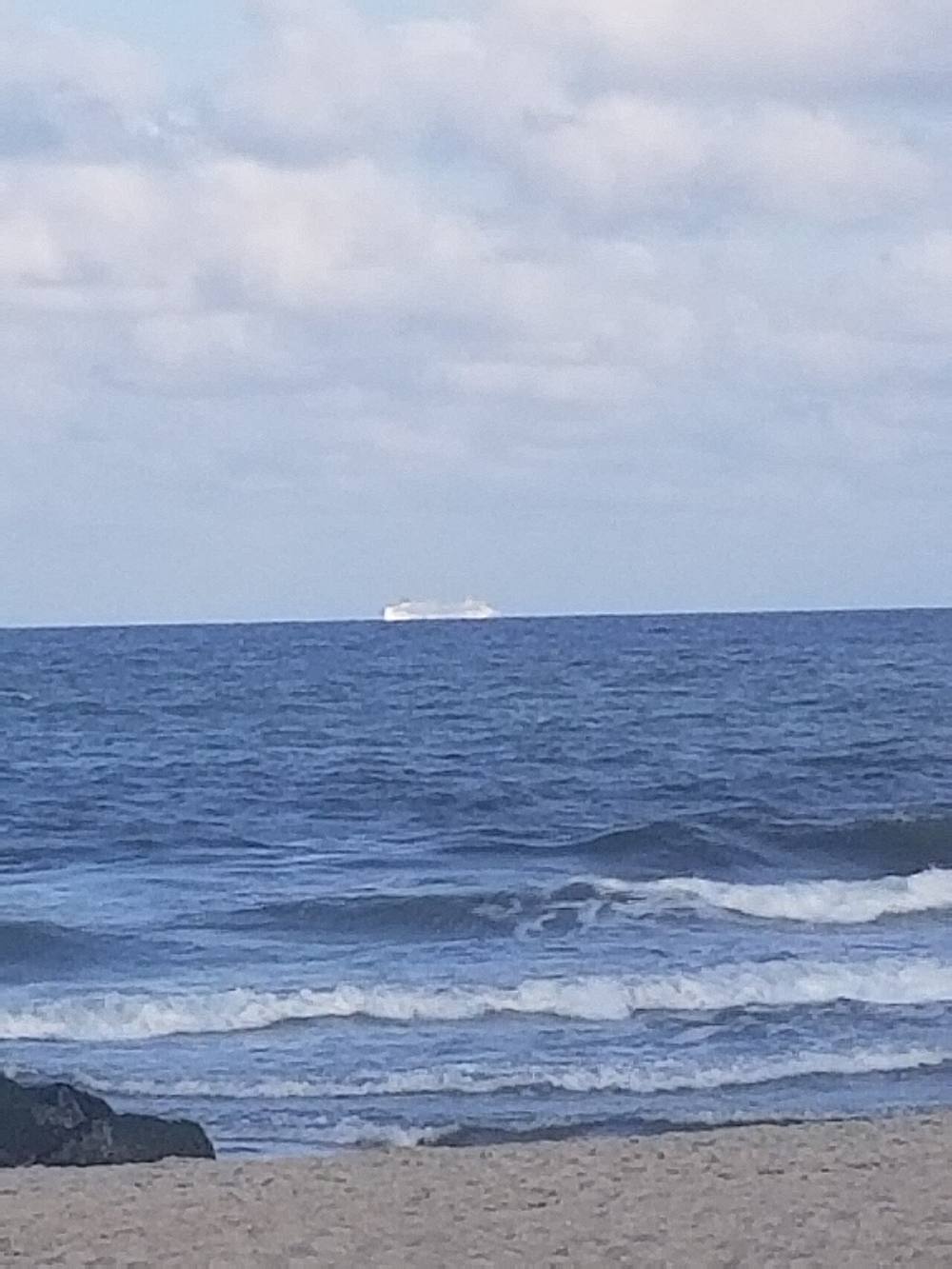 Waves breaking on the beach at Ocean Grove, New Jersey with a ship on the horizon